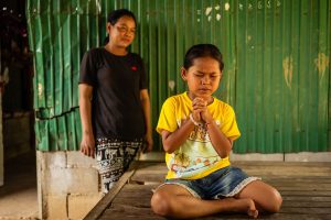 AS HER MOTHER WATCHES, TOLA PRAYS TO THE LORD JESUS CHRIST, ASKING HIM TO LEAD HER PARENTS TO HIMSELF, THE ONLY SAVIOR OF THE WORLD.